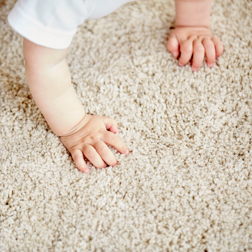 Close-up of a child's hands on a light beige machine washable carpet squares. great alternative to Peel and Stick