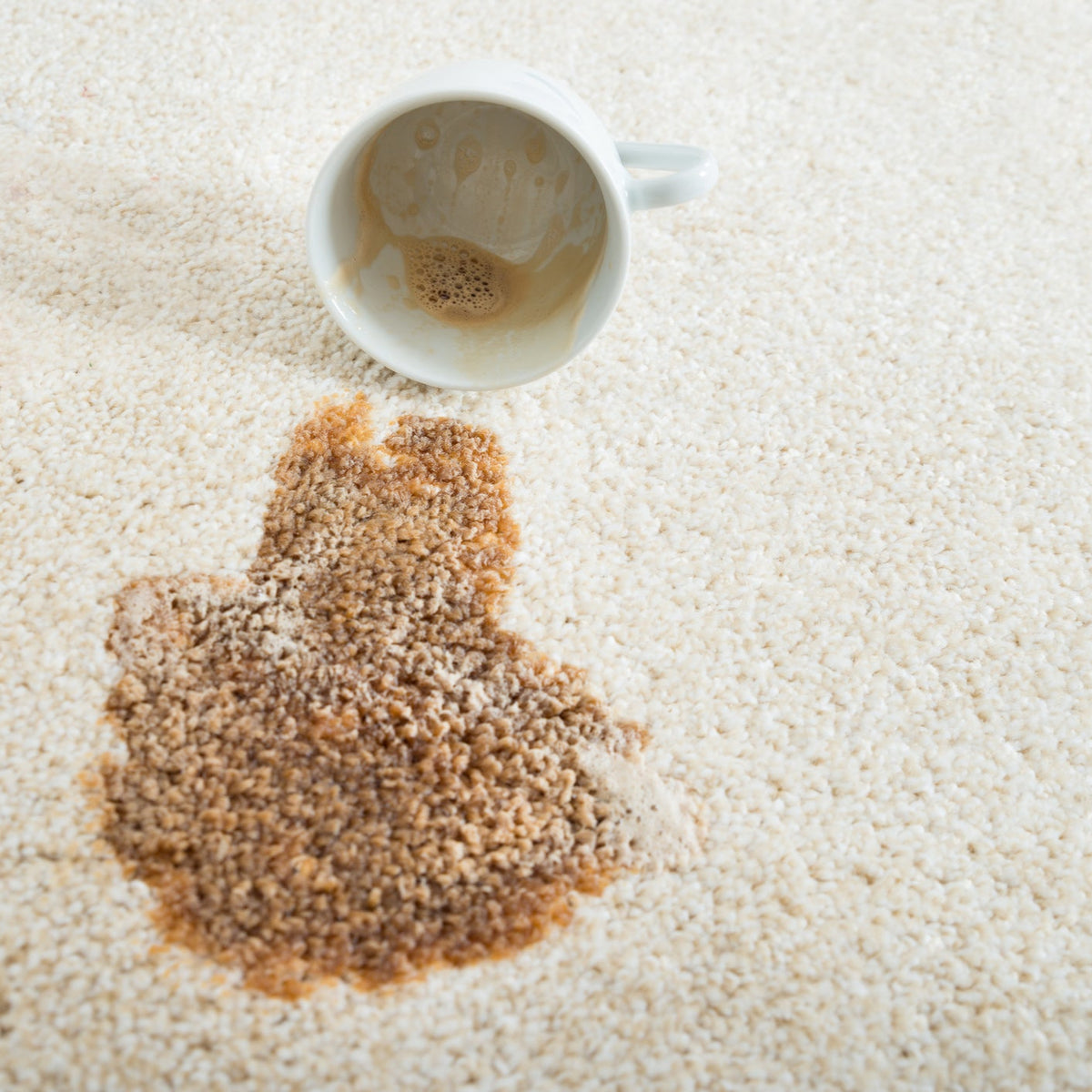 Coffee spill on Atelier Luxury Carpet Tiles with a white mug nearby, demonstrating stain resistance